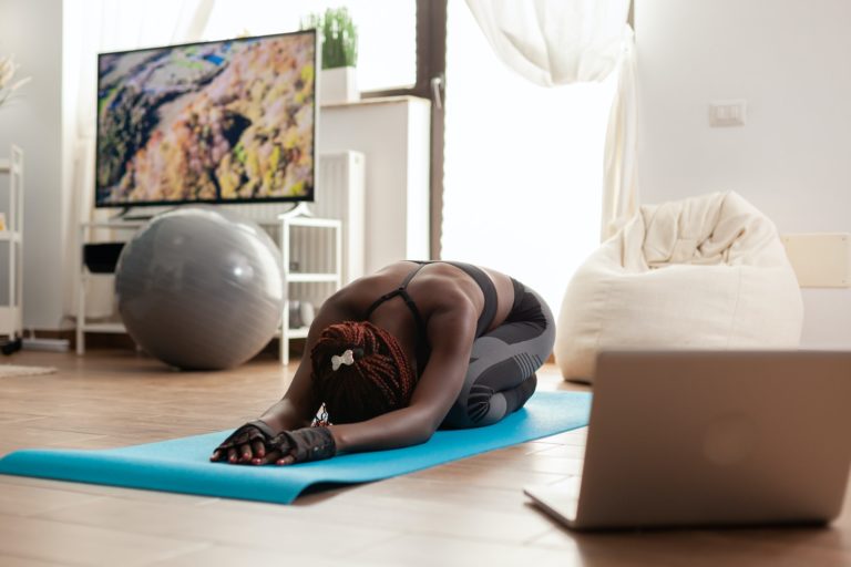 African black fit woman dressed in sportwear relaxing on yoga mat