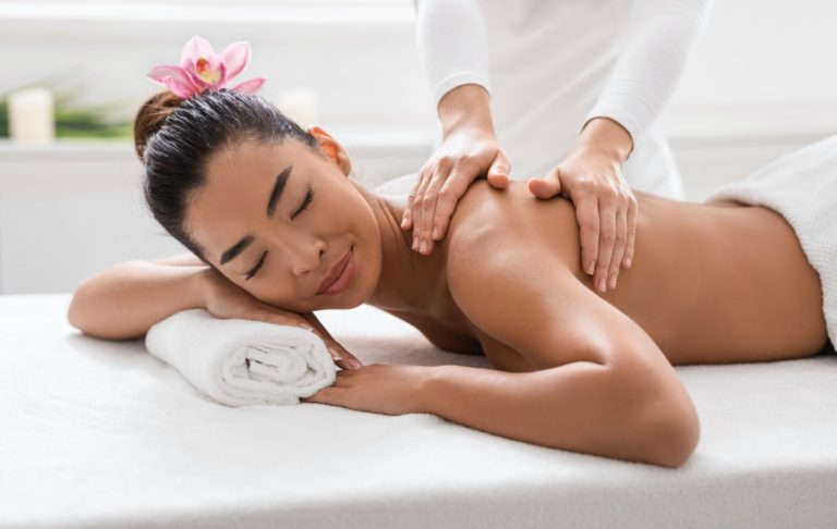 Relaxed Asian Woman Pampering Herself With Body Massage In Spa Salon